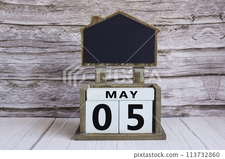 Chalkboard with May 05 date on white cube block on wooden table. Chalkboard with May 05 date on white cube block on wooden table. 113732860