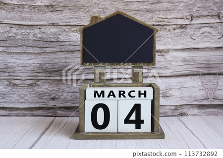 Chalkboard with March 04 date on white cube block on wooden table. Chalkboard with March 04 date on white cube block on wooden table. 113732892