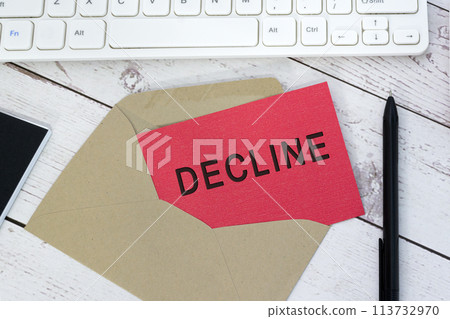 Decline text on red card with envelope, white keyboard and pen on wooden table. Decline text on red card with envelope, white keyboard and pen on wooden table. 113732970