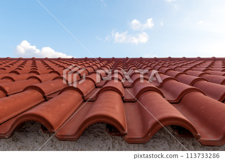 Red tile roof under blue sky. One part is a roof and the other is a pure blue sky. 113733286