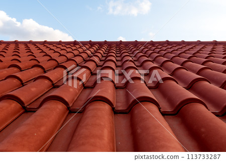 Red tile roof under blue sky. One part is a roof and the other is a pure blue sky. Red tile roof under blue sky. One part is a roof and the other is a pure blue sky. 113733287