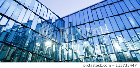 Modern office building with glass facade on a clear sky background. Transparent glass wall Modern office building with glass facade on a clear sky background. Transparent glass wall 113733447
