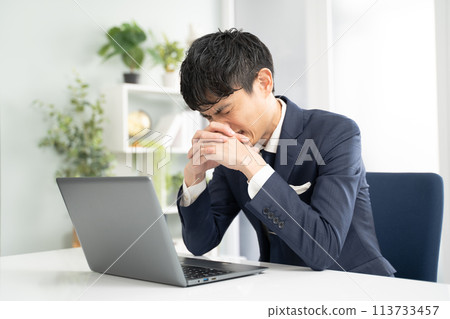 Male businessman worried while working on a laptop Male businessman worried while working on a laptop 113733457