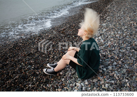Portrait of young girl with short blonde bob hair and green dress on cold sea beach Portrait of young girl with short blonde bob hair and green dress on cold sea beach 113733600