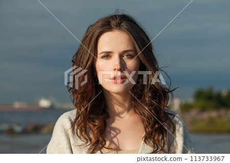 Healthy young woman model with brown hair and natural make-up walking along the shore of the resort 113733967