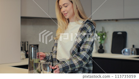 Woman pouring fresh water into glass from jug at home. Health and diet concept. Woman pouring fresh water into glass from jug at home. Health and diet concept. 113735059
