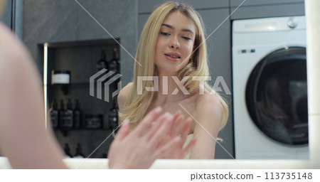 Woman in bathroom using smart mirror. Mirror makes face scan and health. Using health app analyzing the sleep from a tracker. 113735148