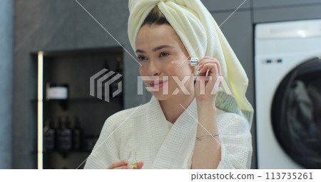 Woman applying hydrogelic serum cream on her face close-up. Natural oil skin care morning routine. 113735261