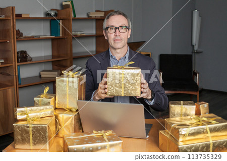 Portrait of mature attractive businessman in glasses and suit with laptop on the table Portrait of mature attractive businessman in glasses and suit with laptop on the table 113735329