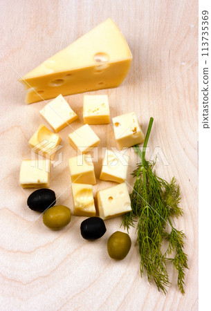 Hard yellow cheese, black and green olives, a sprig of dill on a wooden board. Flat Lay Hard yellow cheese, black and green olives, a sprig of dill on a wooden board. Flat Lay 113735369