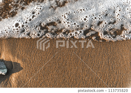 High angle view of stones on beach. Foam on a beach 113735820