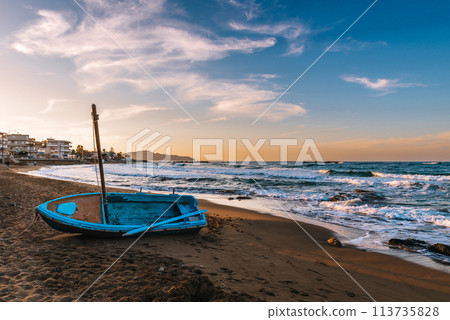 traditional Greek fishing boat on the shore at sunset on Crete, Greece. 113735828