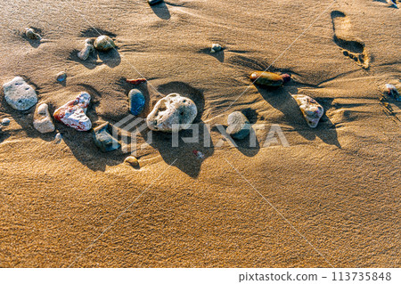 sea sand and stones on the beach at sunset 113735848