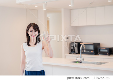 Young woman drinking water at home 113735980