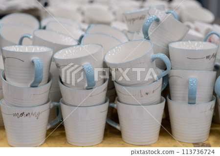 A stack of white mugs and plates in the store for sale. White and clean dishes A stack of white mugs and plates in the store for sale. White and clean dishes 113736724