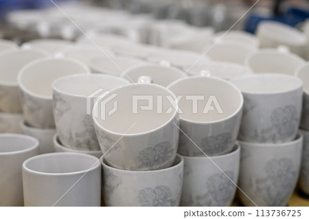 A stack of white mugs and plates in the store for sale. White and clean dishes A stack of white mugs and plates in the store for sale. White and clean dishes 113736725
