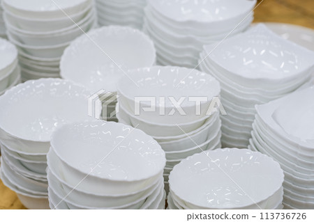 A stack of white mugs and plates in the store for sale. White and clean dishes A stack of white mugs and plates in the store for sale. White and clean dishes 113736726