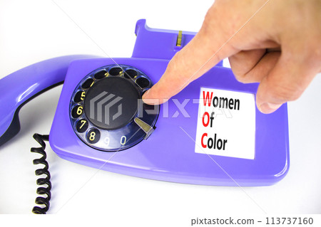 WOC women of color symbol. Concept words WOC women of color on beautiful old disk phone. Beautiful white background. Businessman hand. Business WOC women of color social issues concept. Copy space. 113737160