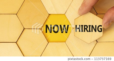 Now hiring symbol. Concept words Now hiring on beautiful wooden puzzle. Beautiful yellow background. Businessman hand. Business marketing, motivational now hiring concept. Copy space. 113737169