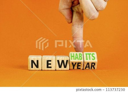New year and habits symbol. Concept word New year New habits on wooden cubes. Beautiful orange table orange background. Psychologist hand. Psychological new year and habits concept. Copy space. New year and habits symbol. Concept word New year New habits on wooden cubes. Beautiful orange table orange background. Psychologist hand. Psychological new year and habits concept. Copy space. 113737230