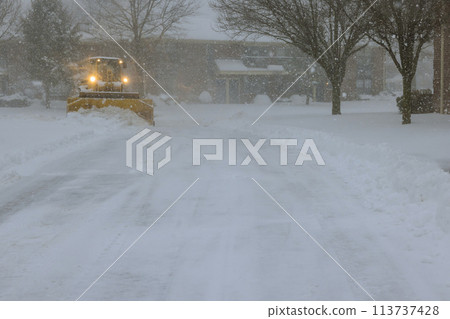 An ice plough removes snow from parking lot during a heavy snowfall snowstorm An ice plough removes snow from parking lot during a heavy snowfall snowstorm 113737428