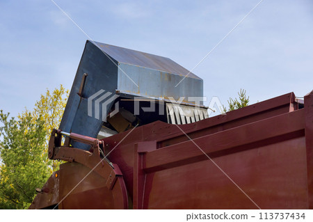Suburban garbage disposal service truck a trash can into a garbage truck. 113737434