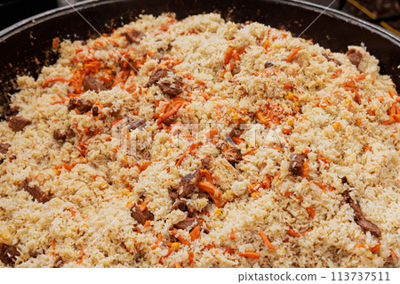 In a street food festival, Uzbek pilaf is being prepared in cauldron In a street food festival, Uzbek pilaf is being prepared in cauldron 113737511