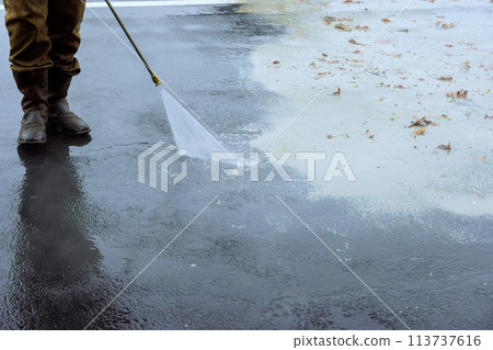 Street is sprayed clean using pressurized water, wet washing to clean it Street is sprayed clean using pressurized water, wet washing to clean it 113737616