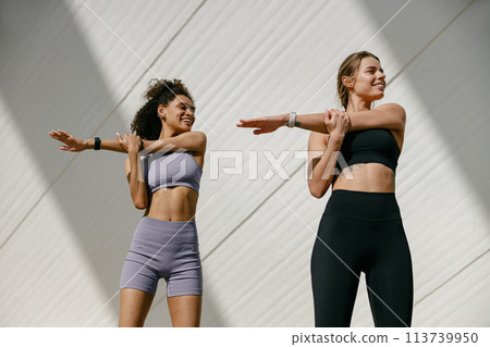 Smiling women does warm-up exercises in morning before running training outside. Healthy fitness 113739950