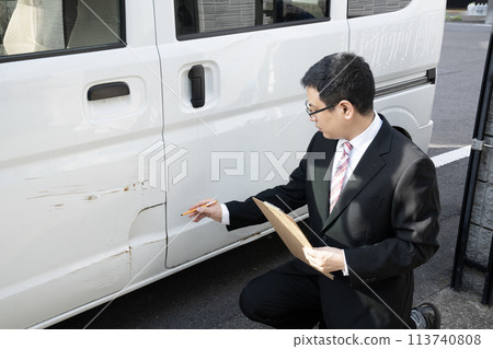 A salesman giving an estimate for repairing a damaged car 113740808