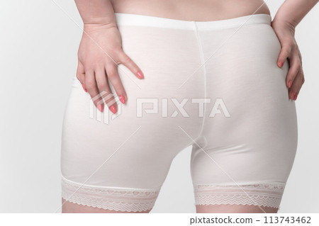 Unidentified middle aged woman is shown in closeup rear view wearing pantaloons and placing her palms on buttocks. Image represents concepts of body consciousness and body positivity in adulthood Unidentified middle aged woman is shown in closeup rear view wearing pantaloons and placing her palms on buttocks. Image represents concepts of body consciousness and body positivity in adulthood 113743462