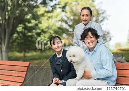 A dog lover's family, daughter, father and mother walking their dog sitting on a bench in the park 113744701