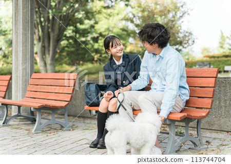 愛狗人士的父母、女兒和父親坐在公園的長凳上遛狗 113744704