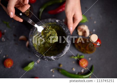 woman mixing green sauce in a stone marble mortar woman mixing green sauce in a stone marble mortar 113745251