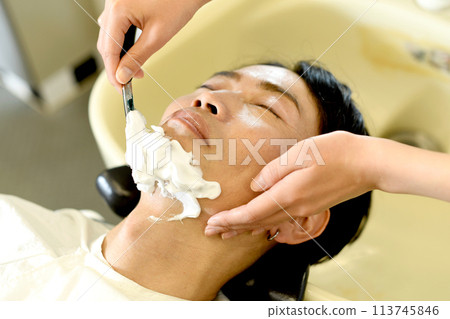 Asian man getting shaved at a barber shop 113745846
