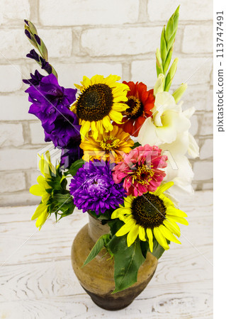 Bouquet of flowers in antique rustic clay jug against white brick wall Bouquet of flowers in antique rustic clay jug against white brick wall 113747491
