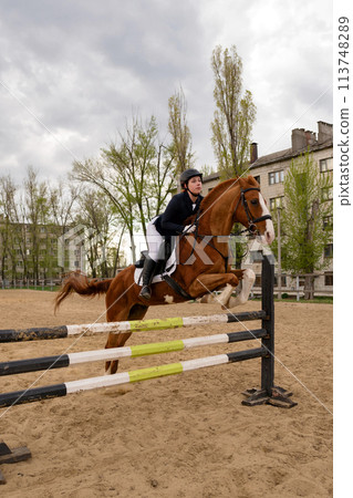 Focused rider clearing jump with horse, vertical shot. Focused rider clearing jump with horse, vertical shot. 113748289