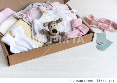 Baby and child clothes and knitted toys in carton box. 113749424