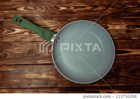 Frying Pan With Green Handle on Wooden Table 113750208
