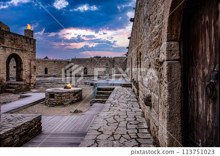 Stone building with wooden door and stairs in a city landscape with cloudy sky Stone building with wooden door and stairs in a city landscape with cloudy sky 113751023