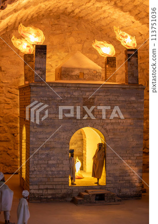 Group in front of holy place building with amber flames from brick chimneys 113751036