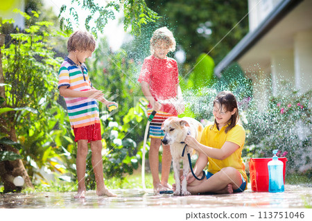 Kids wash dog in summer garden. Water hose fun. Kids wash dog in summer garden. Water hose fun. 113751046