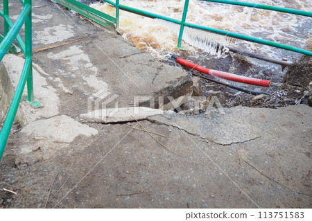 Spring flood. Rushing water in the river. Dark ferrous water rushes in the stream. Karelia, Lososinka River in spring. Floods, tsunami and climate change. Destroyed bridge with pipes. Weather disaster 113751583