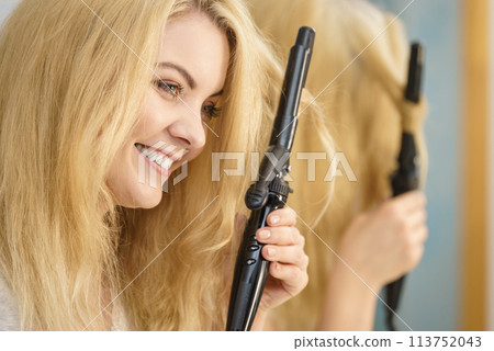 Woman using hair curler 113752043