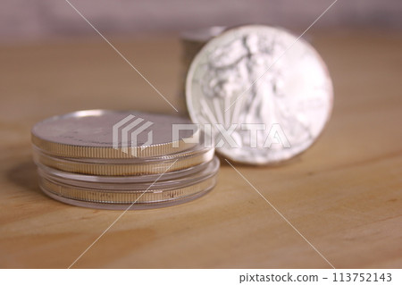 Stacks of American Silver Eagle Coins on Wooden Table 113752143