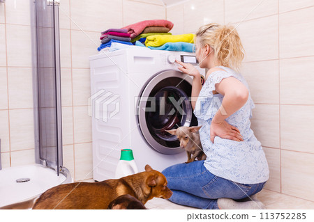 Woman starting washing machine. Woman starting washing machine. 113752285