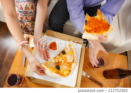 Couple eating pizza with red sauce Couple eating pizza with red sauce 113752902