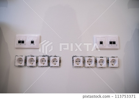 Two white electrical outlets blended into a monochrome wall 113753371