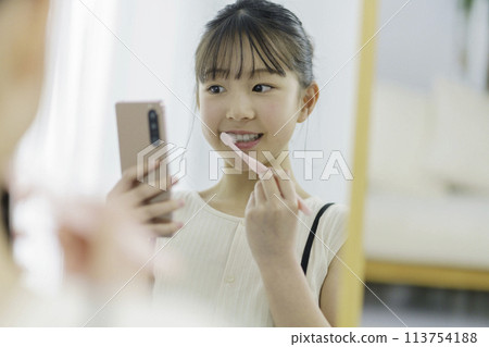 A girl in elementary school looks at her smartphone while brushing her teeth in the morning 113754188