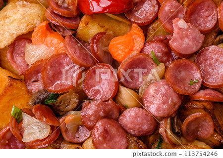 Grilled potatoes cut into slices with hunting sausages with garlic, onion 113754246